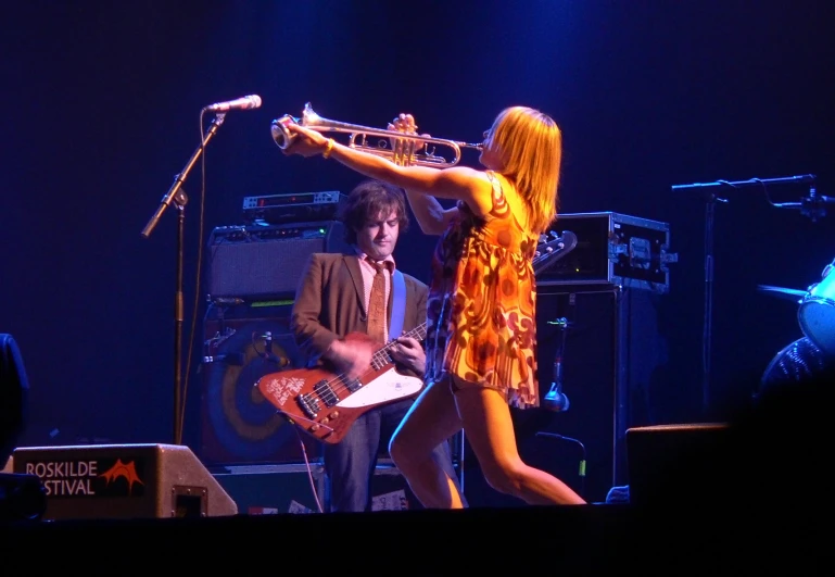 two woman standing on stage holding guitars and another lady with long hair