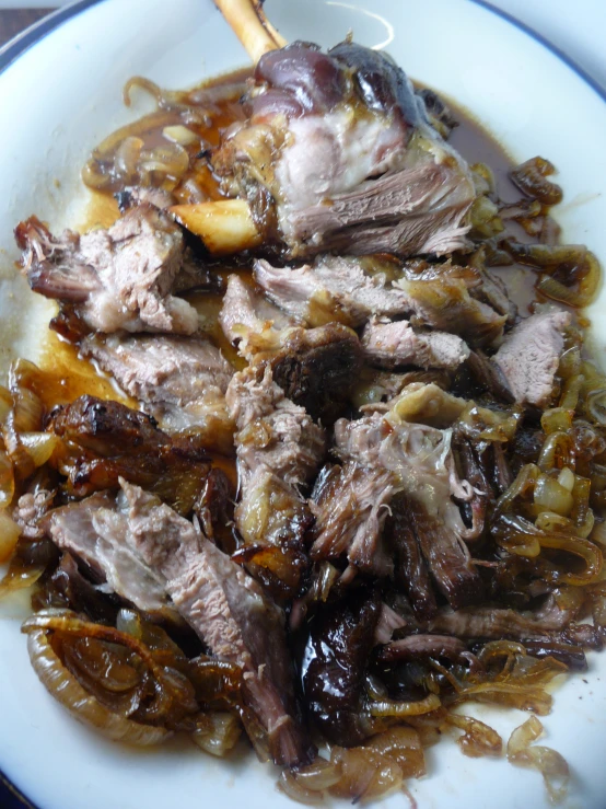 a white plate topped with meat and onions next to two chop sticks