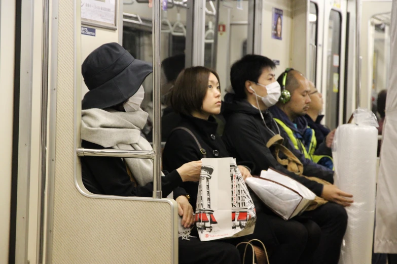 people wearing masks are sitting in a subway car