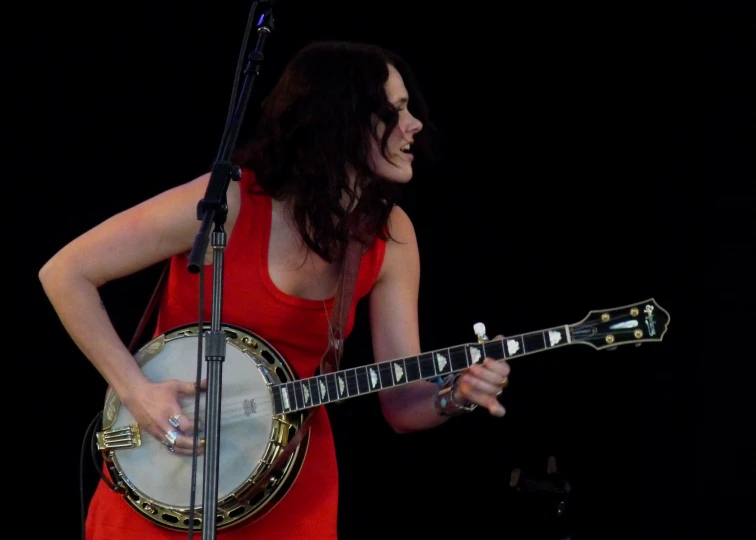 the woman is holding a instrument and singing into a microphone