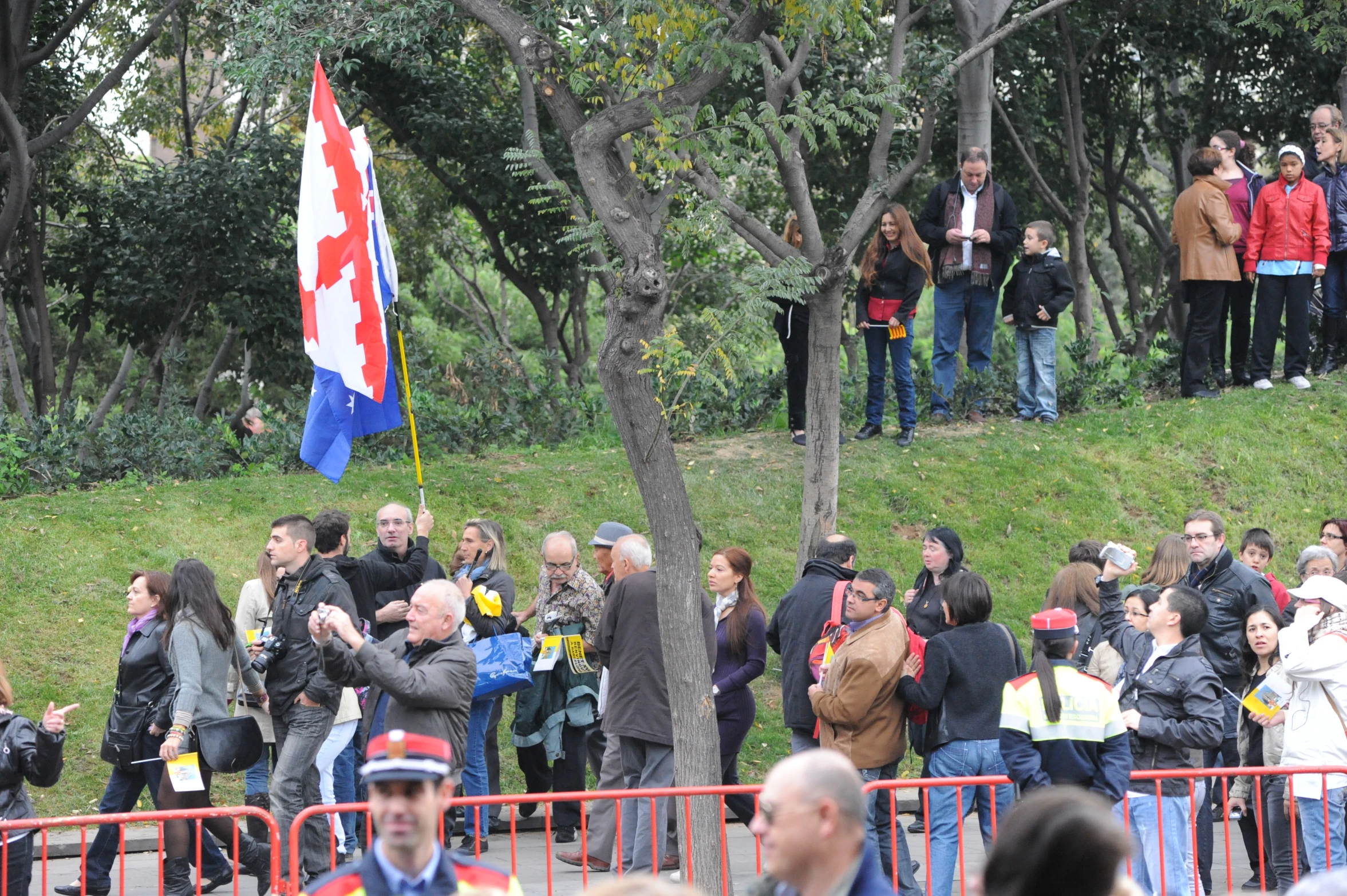 a large crowd in a park watching two people fly an kite