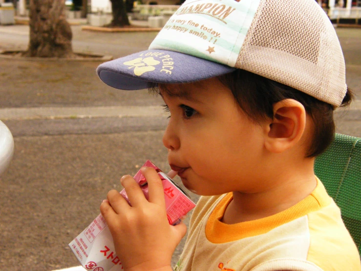 a little boy on the street eating soing from a small bag
