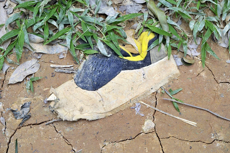 a broken shoe sitting on top of a dirty ground