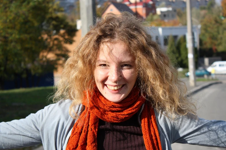 a woman in a scarf standing in the street smiling