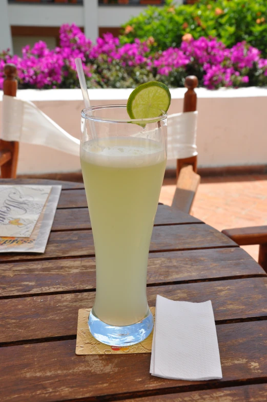 a tall glass on a table with some lemon wedges on it