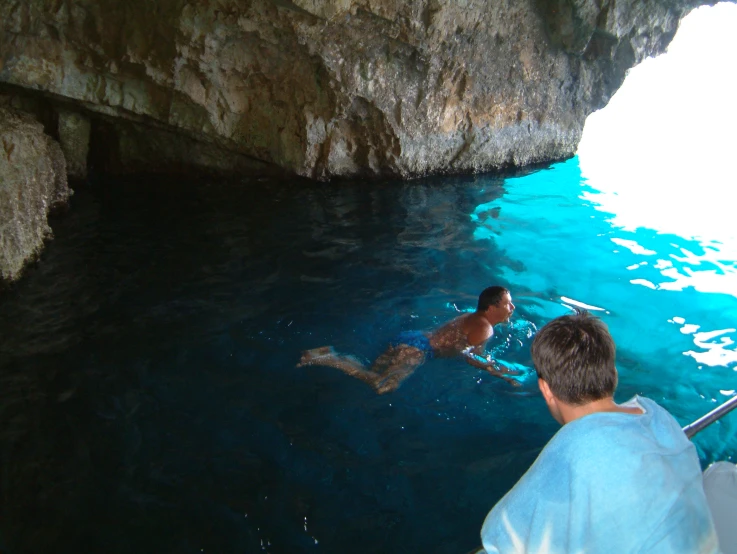 a man is swimming in the water near an area of caves