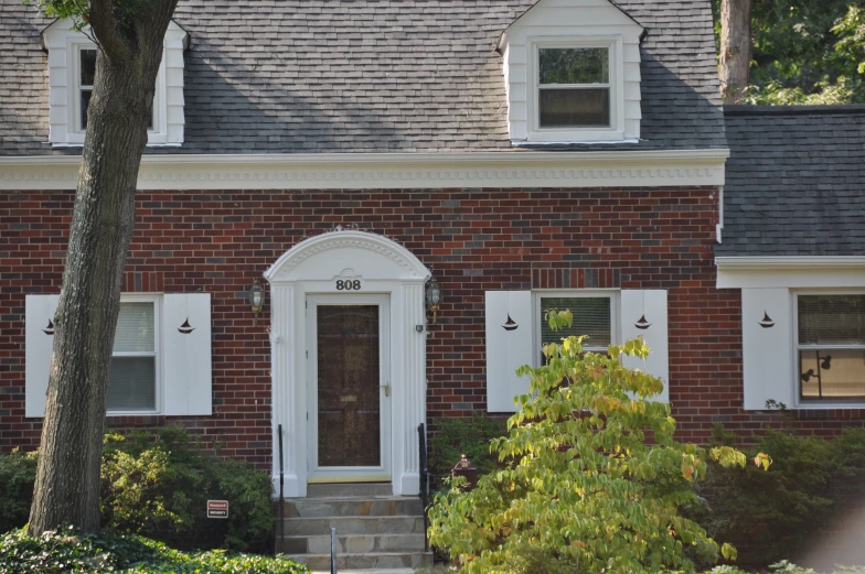 a brick home with two white doors and a brown front door