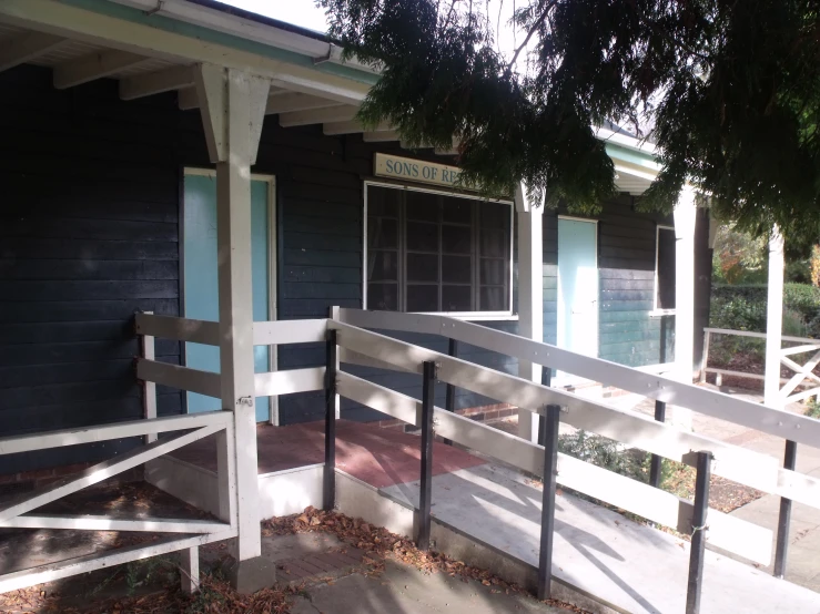 the door to a black building has a porch and fence