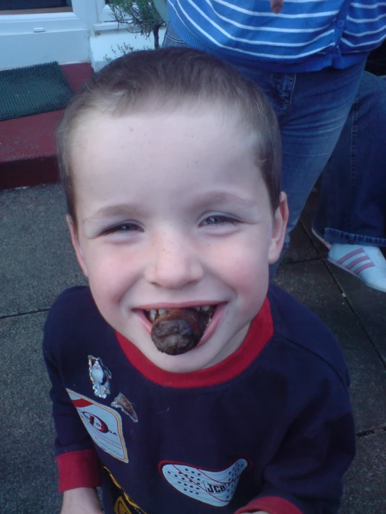 a toddler in a red and blue shirt eating a dog treat