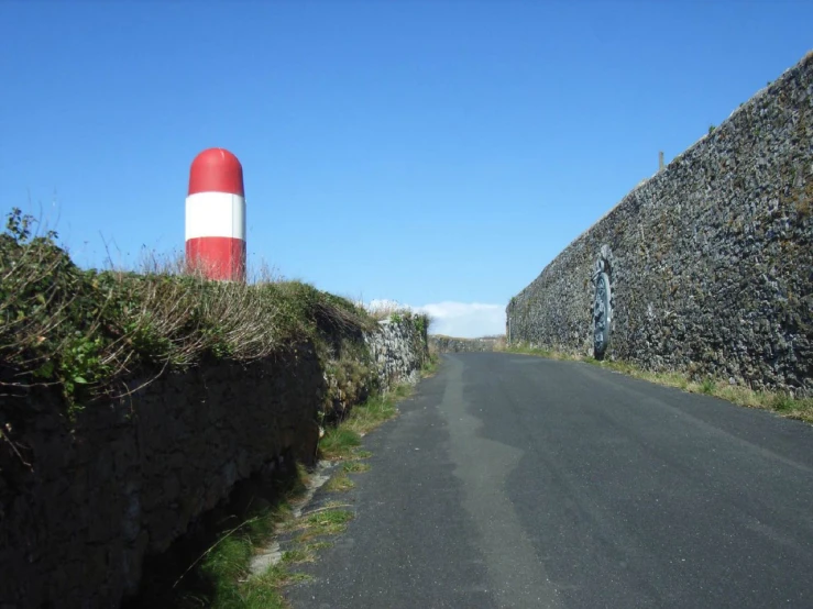 an orange and white striped buoy is standing on the side of a road