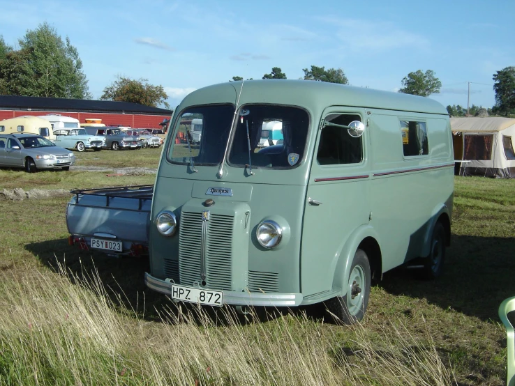 an old vehicle sits parked in the middle of a field