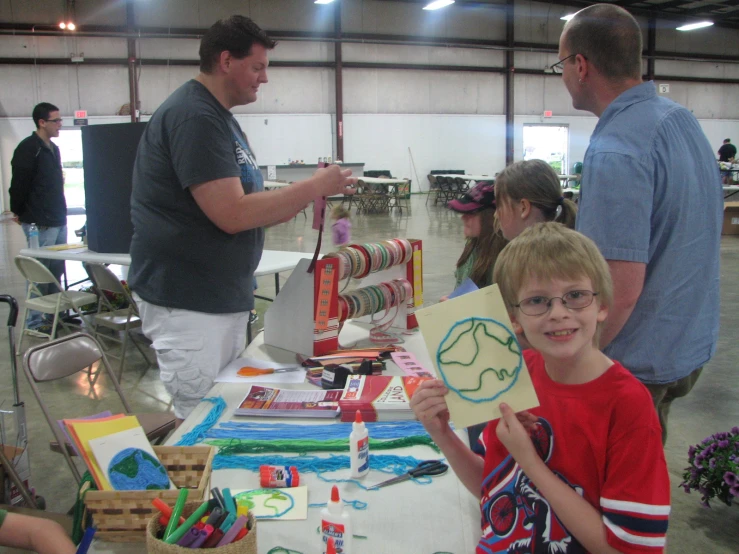 there is a boy showing off crafts for his friends