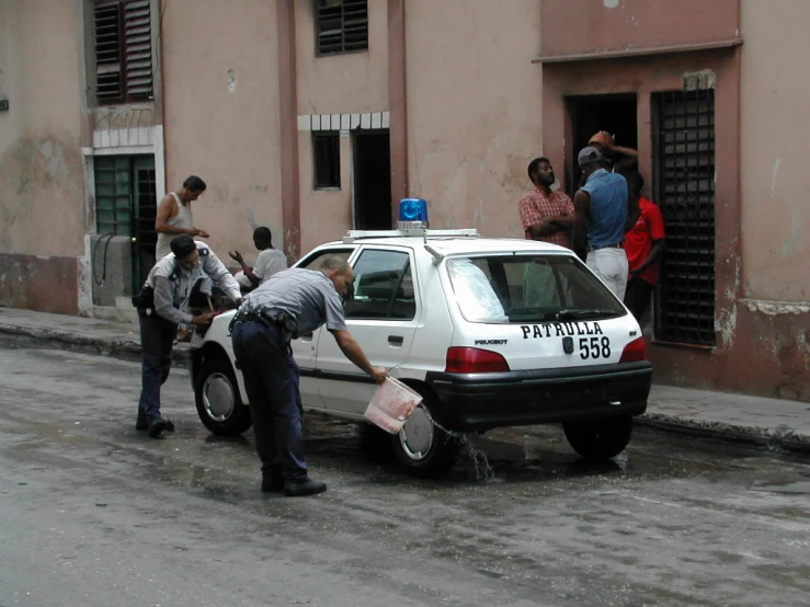 a car parked on the side of the road and people standing around