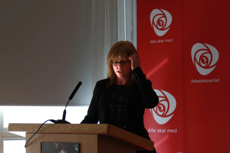 a woman standing at a podium speaking into her phone