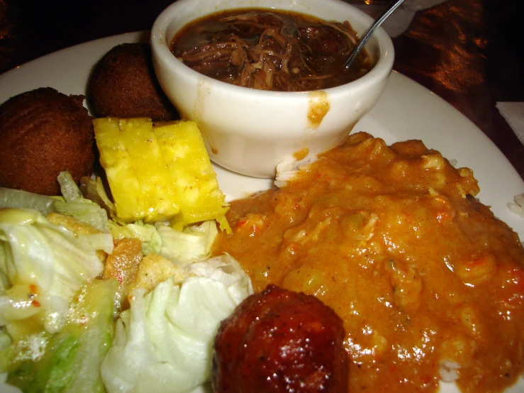 a white plate with two sides of soup, and two cheese balls