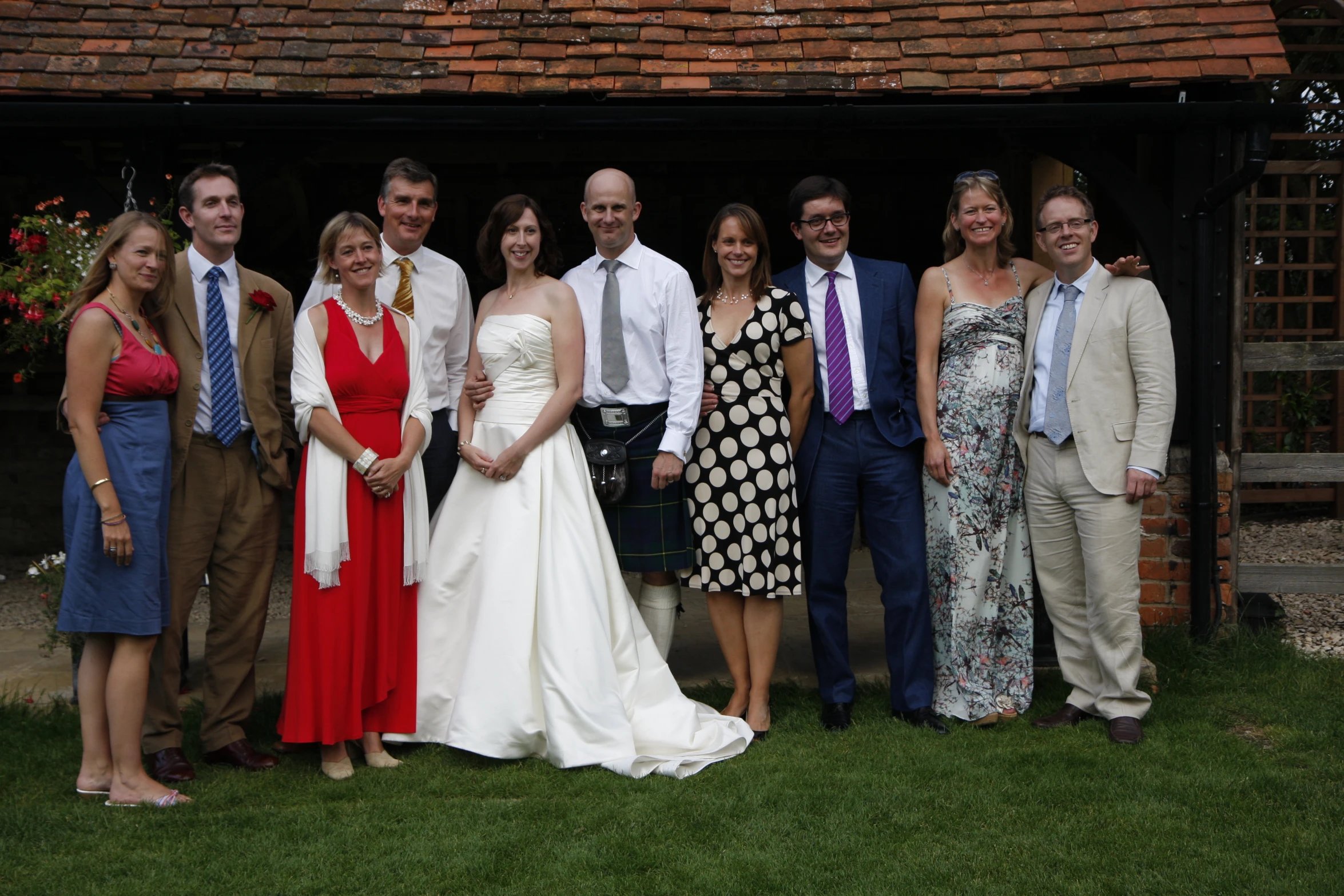 group of people in wedding dresses and dress suits posing for the camera