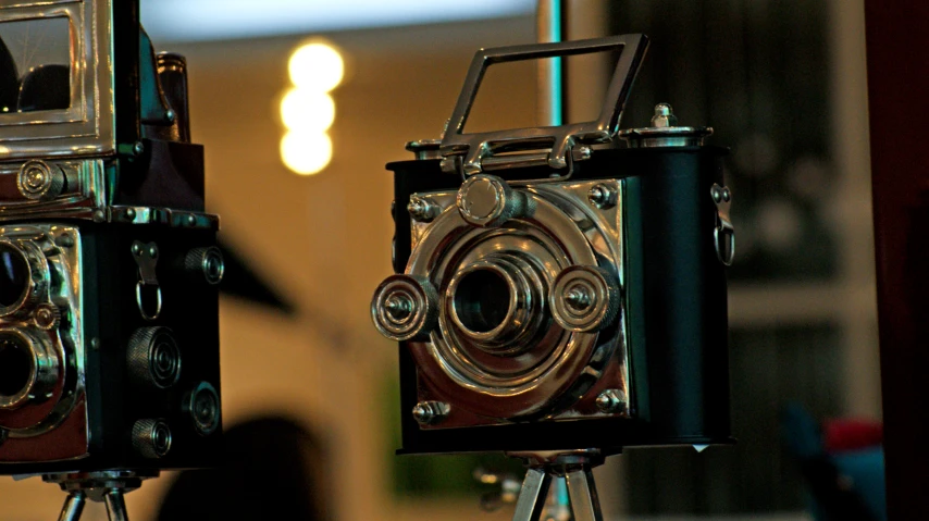 two antique cameras are seen in front of some lights