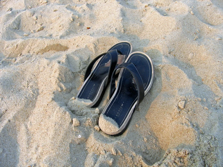 two blue and white shoes that are on some sand