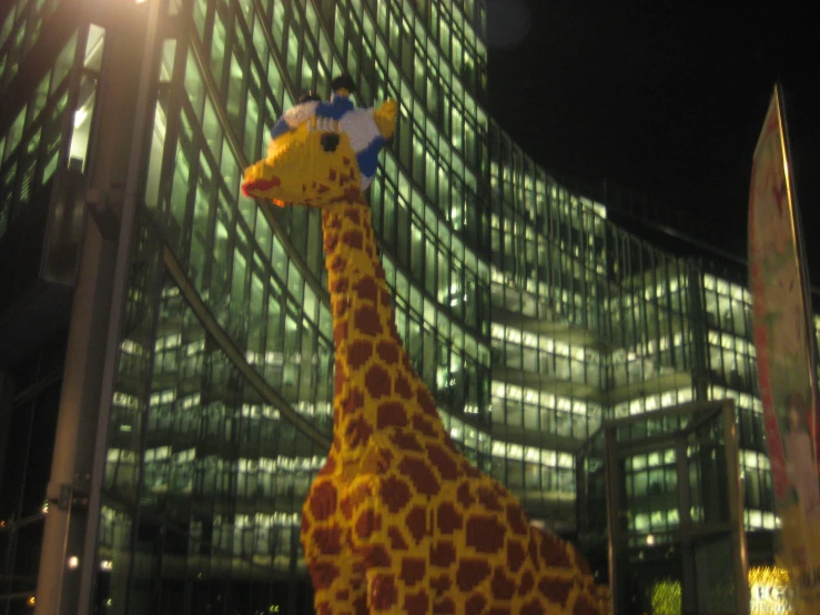 a very large fake giraffe sitting in front of a tall building