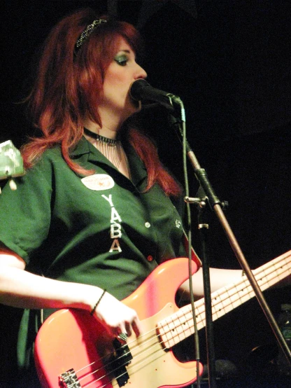 a young red haired woman plays the bass