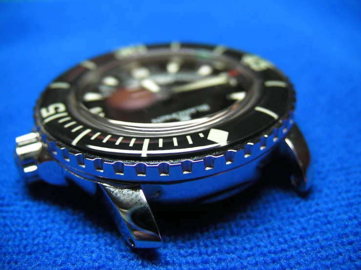 the watch is black and silver on a blue cloth