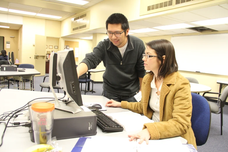 a couple of people sitting at a computer together