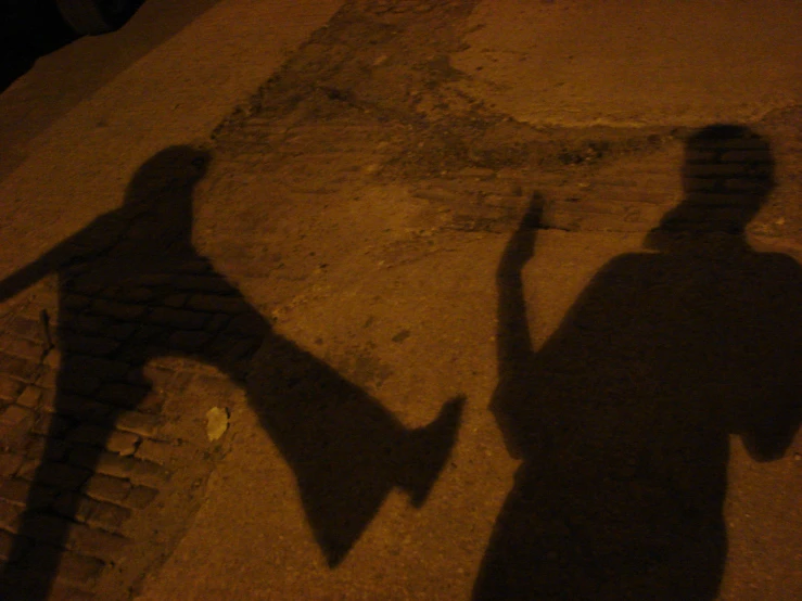 the shadow of two people standing on the sidewalk