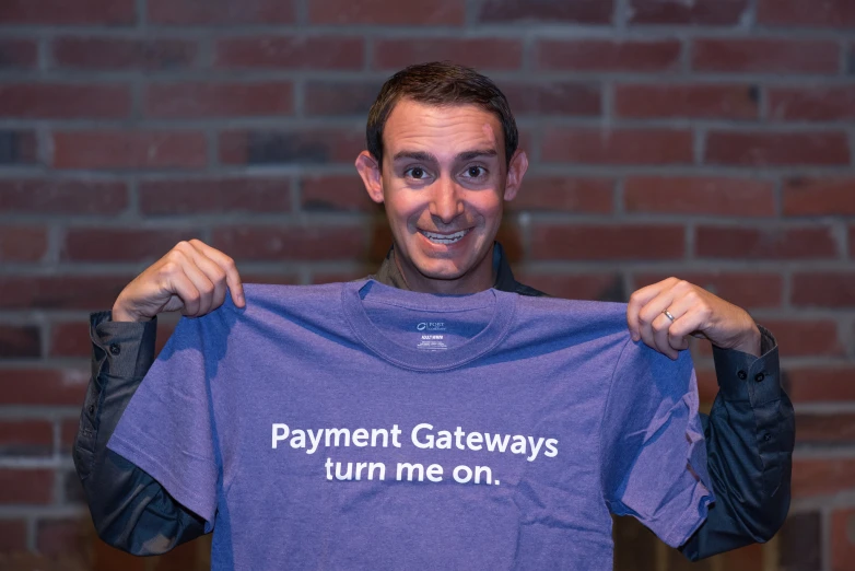 the man is showing off his t - shirt in front of a brick wall