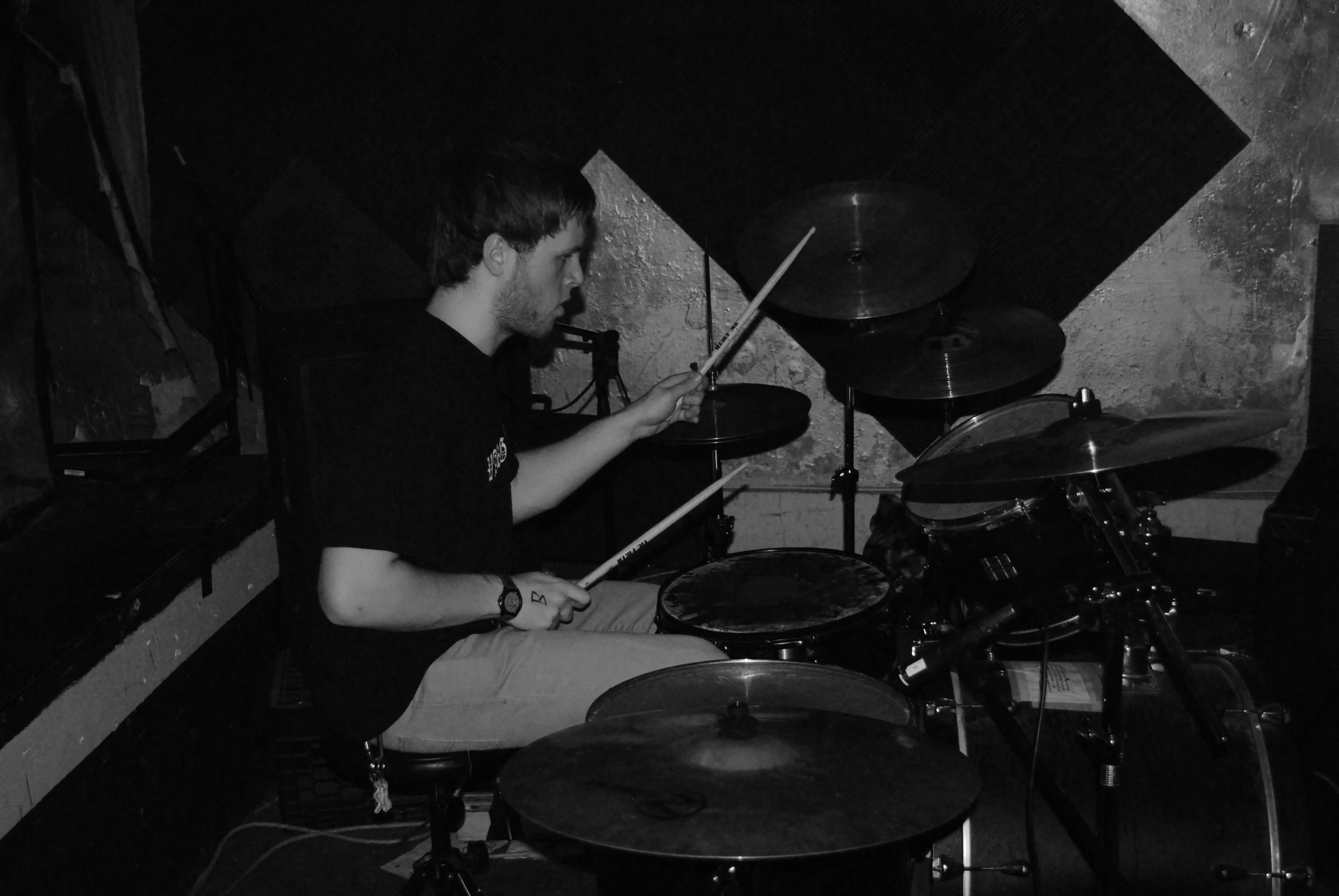 a man that is sitting down in front of a drum set