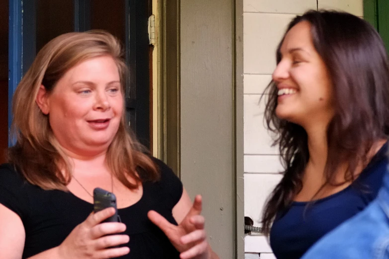 two women are talking together as they smile