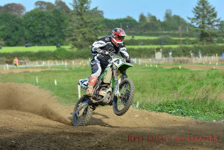 a man riding on the back of a dirt bike through a grass field