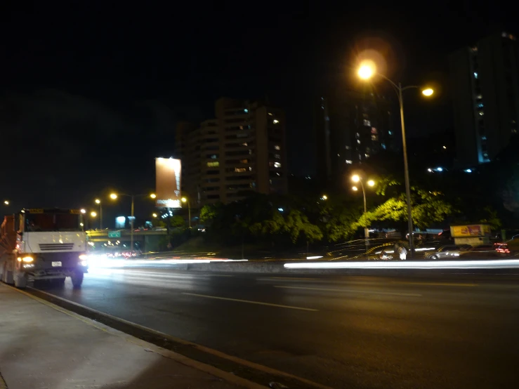 a city street at night with the lights of buildings reflecting off of the road