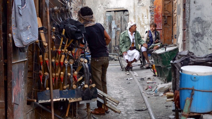 a group of men sit on a chair in a run down alleyway