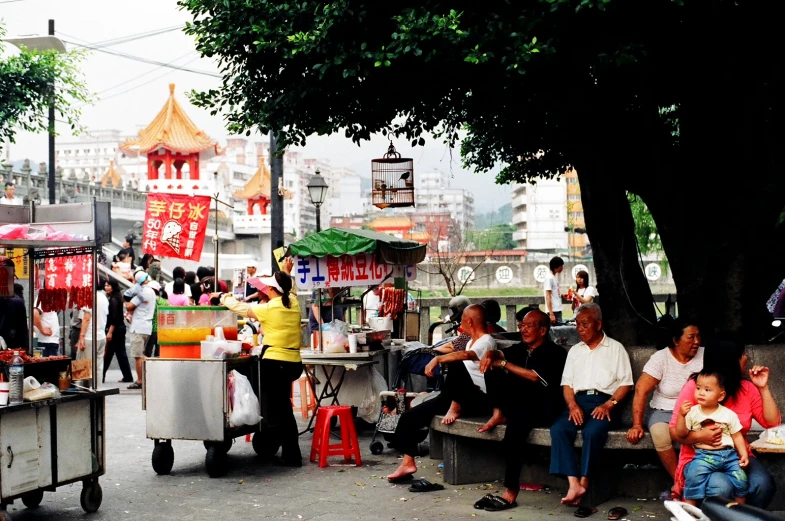 a number of people sitting on some benches near trees