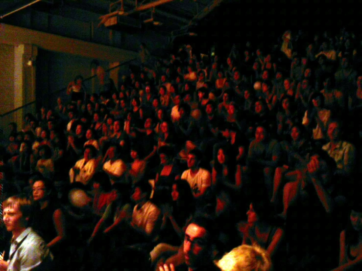 there is a man standing at the front of a packed auditorium