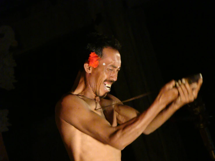 a man with an orange flower on his head playing the tambor