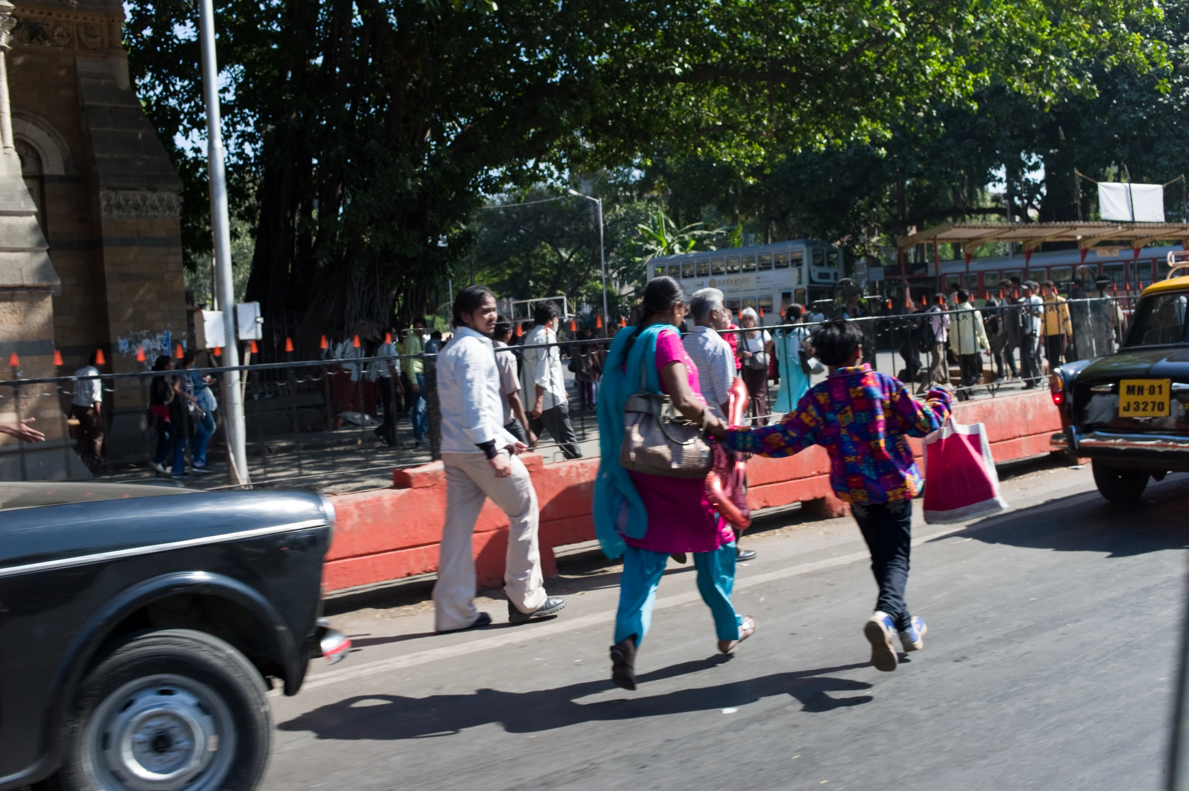 several people walking in front of a yellow bus on the street