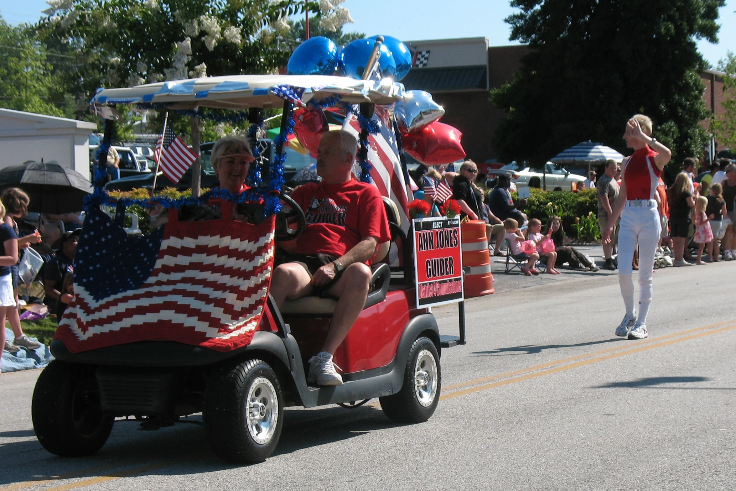 people in a street with patriotic decor and balloons