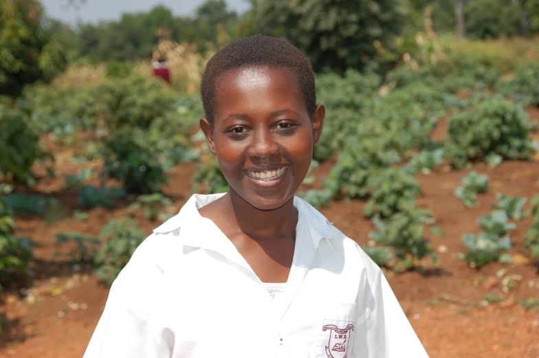 a young black woman in white is smiling and wearing a white shirt