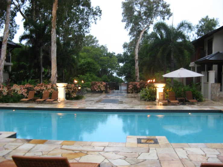 an outdoor swimming pool with several lounge chairs and umbrellas