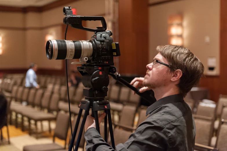 a man holding a video camera in front of a conference room