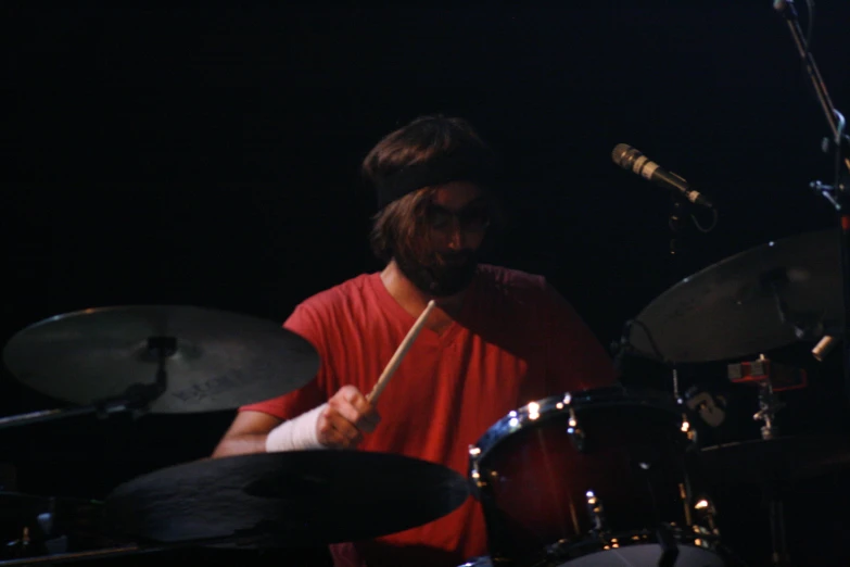 a man playing drums while standing next to a microphone