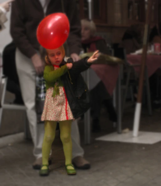  holding a red balloon while standing on brick floor