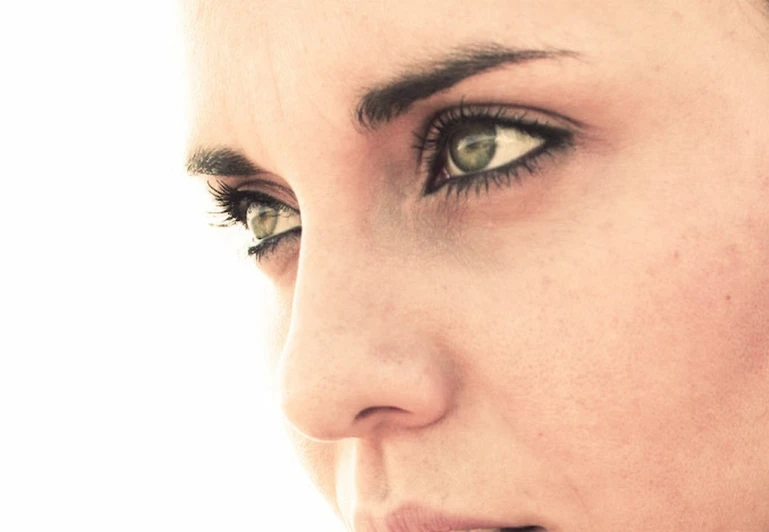 a woman's green eyes and eyelashes with the side of her face showing