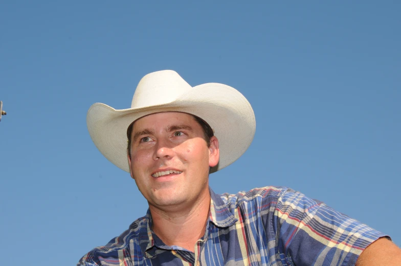 a man wearing a cowboy hat and looking at soing