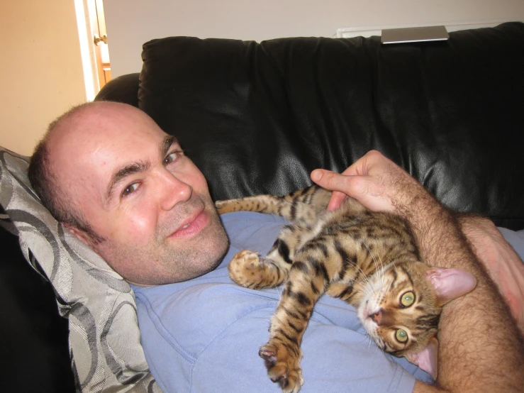 a man laying on the couch with a cat in his lap