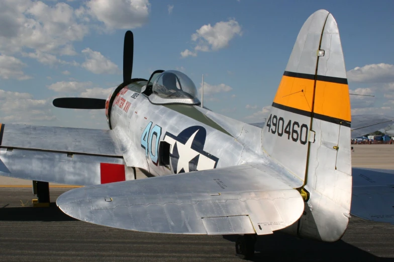 small silver plane sits on the runway under a cloudy sky