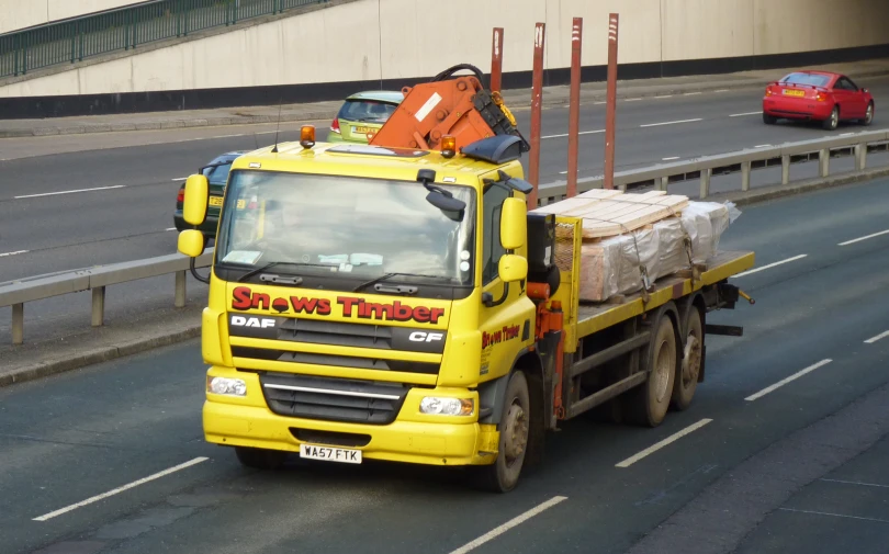 a yellow truck with many items on it riding down the road