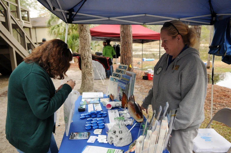 two woman standing behind a table selling food at an event