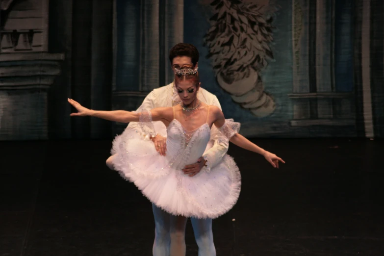 a man and woman in ballet attire dance on stage